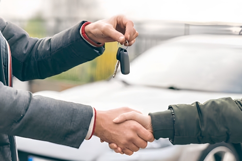 Customer receiving vehicle keys during a successful car purchase.