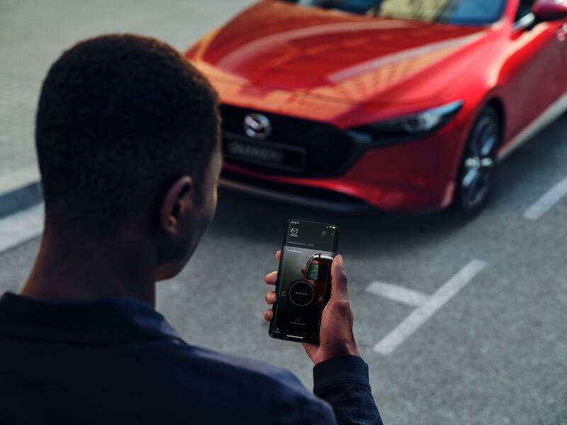 A man using the MyMazda mobile app to lock the Mazda3