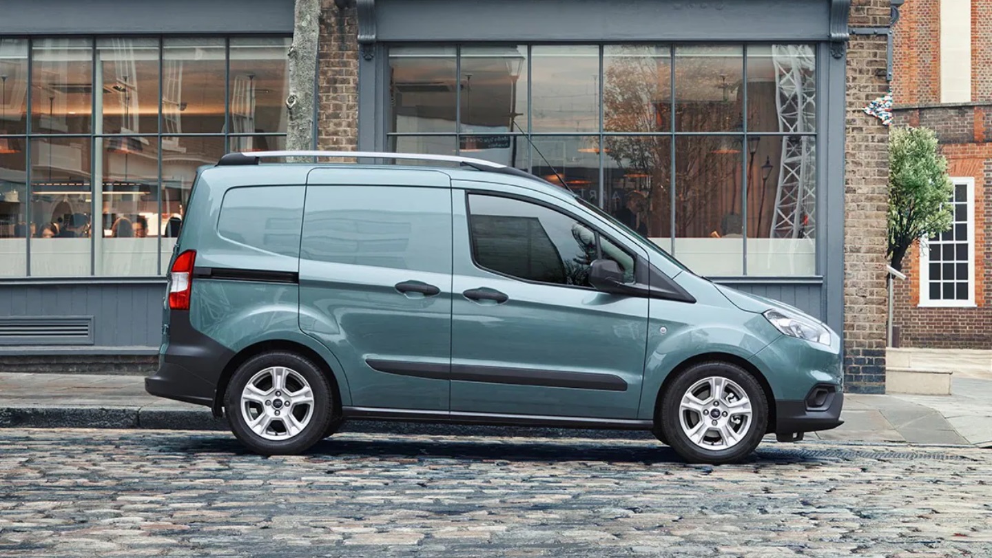 Blue Ford Transit Courier driving along cobbled road