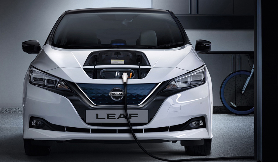 White Nissan LEAF charging in a modern garage