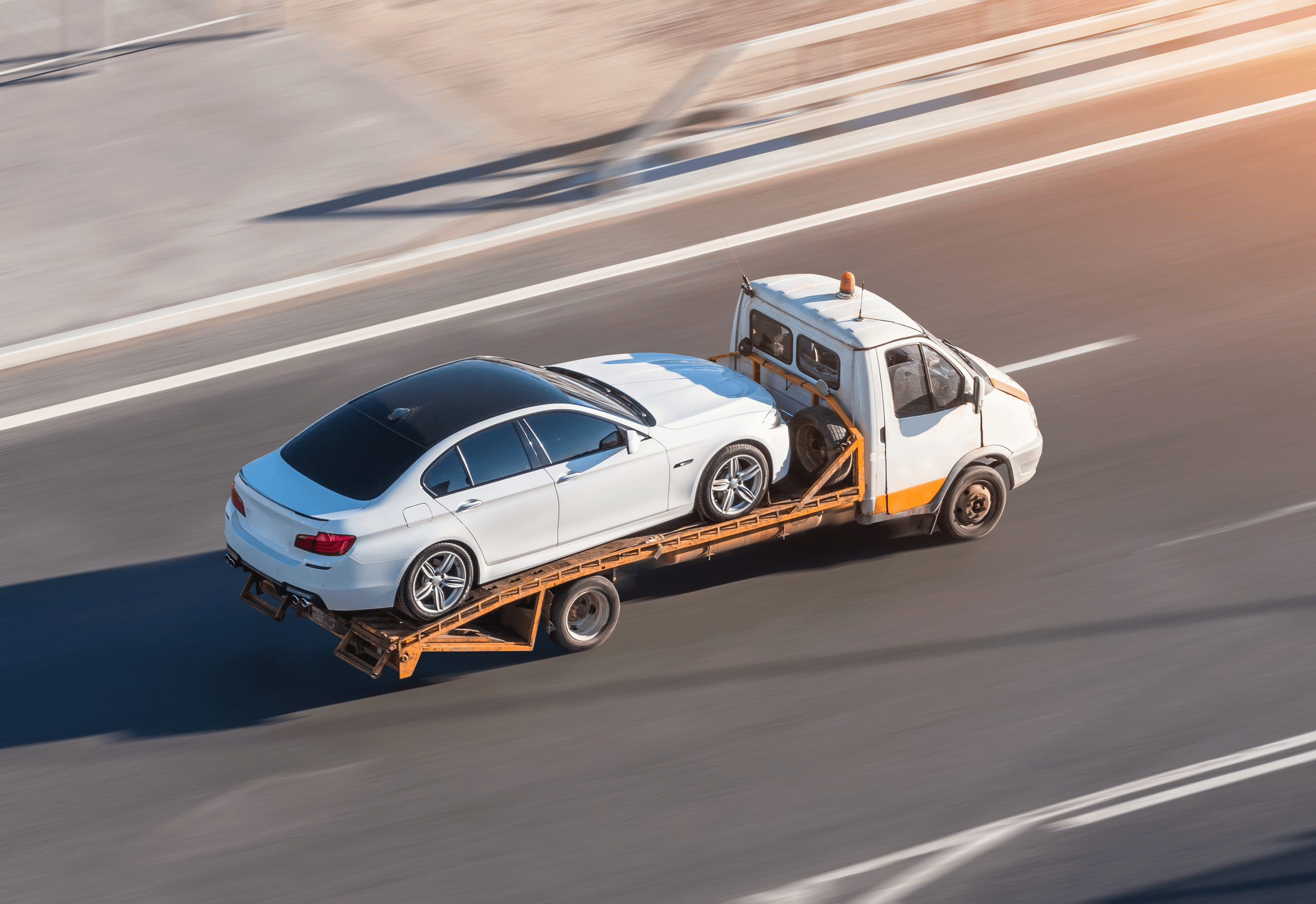 White car on the back of a recovery wagon.