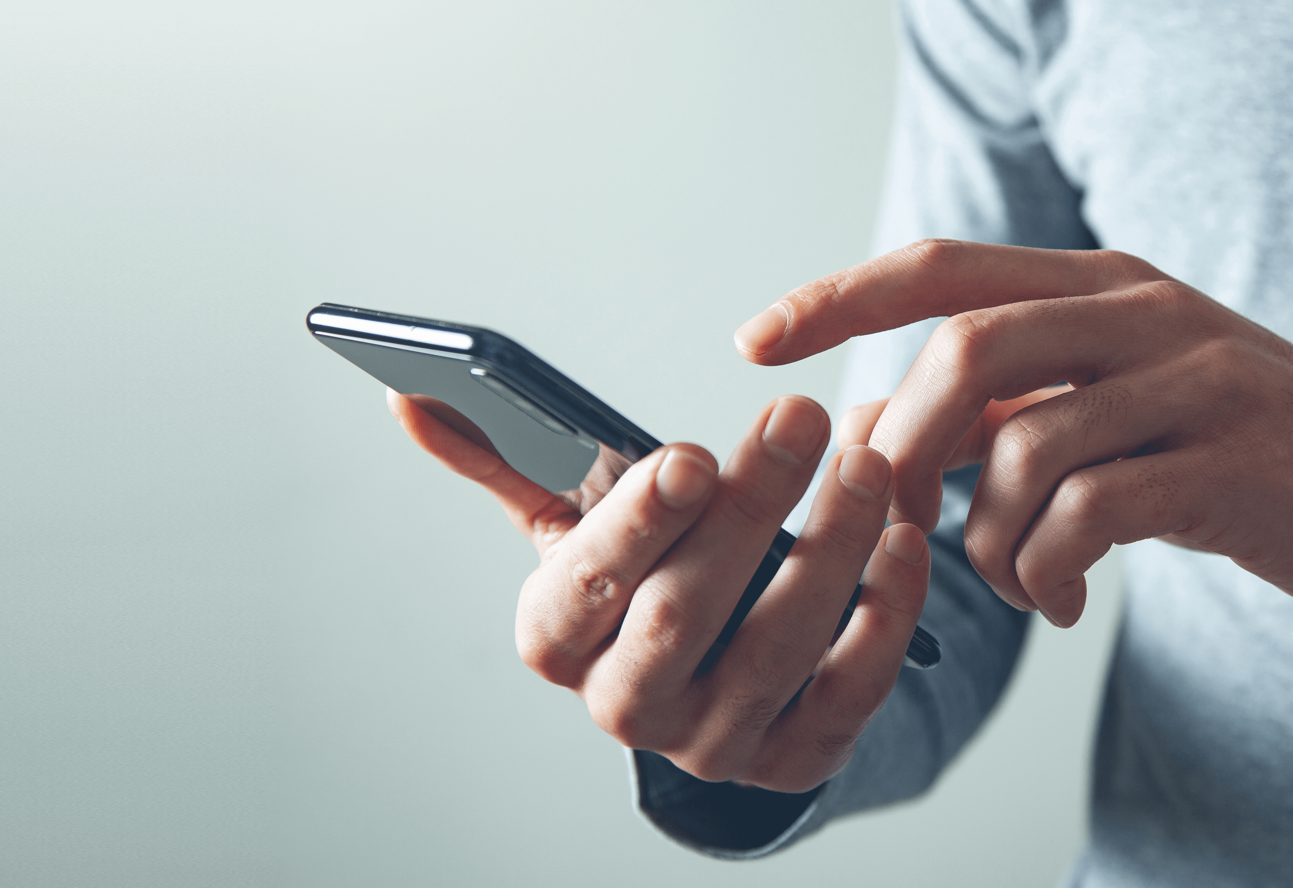 Hand holding iPhone whilst other hand is tapping on the screen.