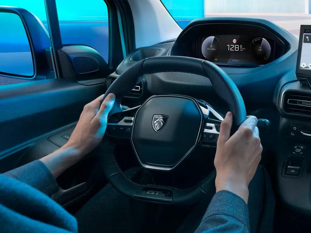 Driver-focused Peugeot commercial vehicle cockpit with multifunction steering wheel and digital instrument display.