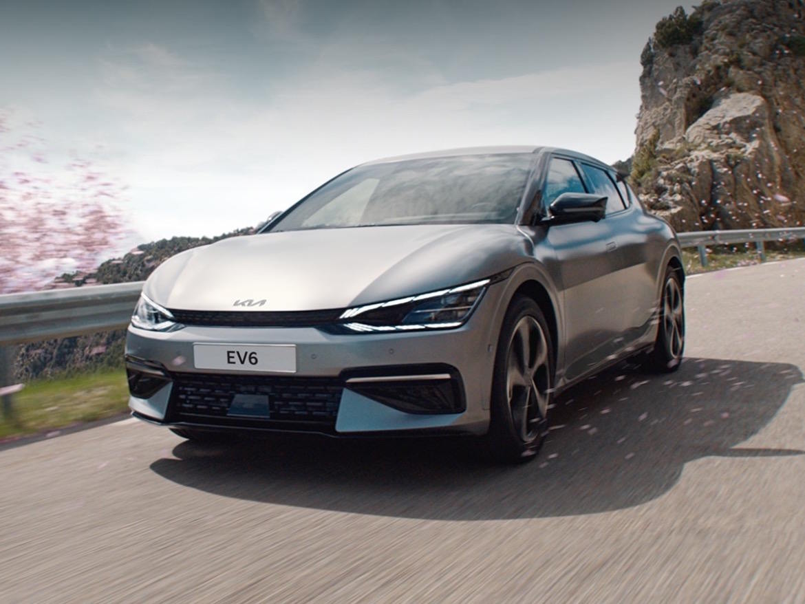 Kia EV6 driving on a scenic road, showcasing innovative electric performance and dynamic styling.