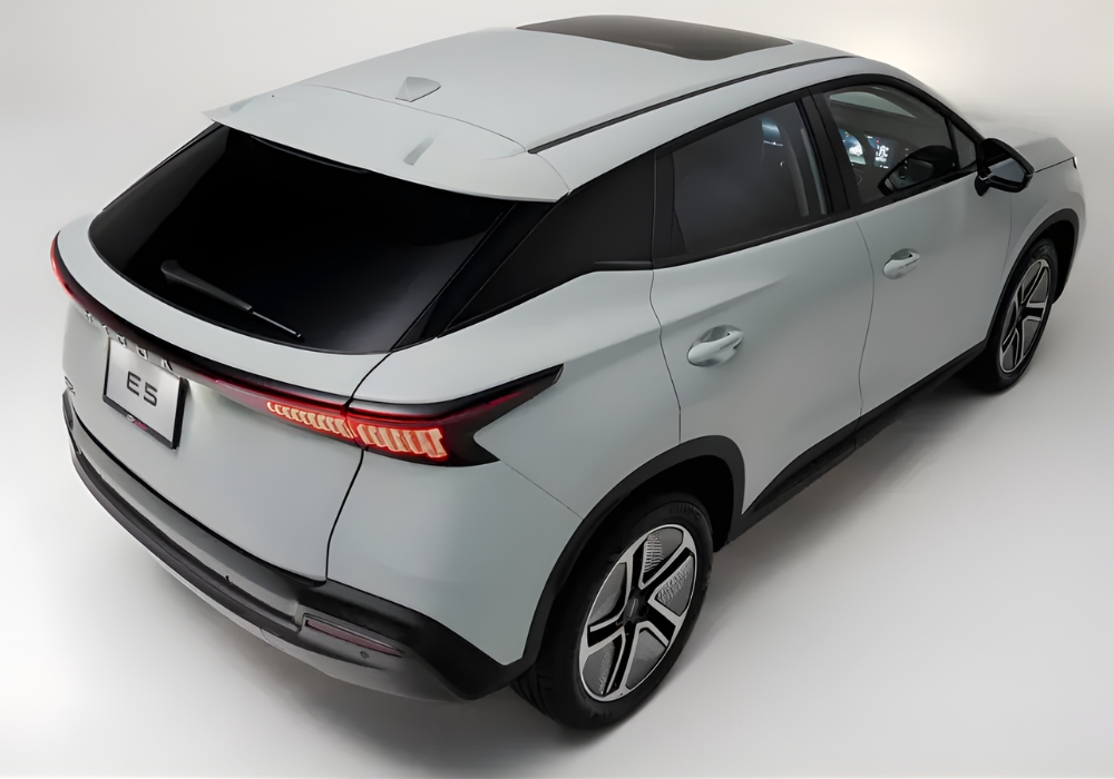 High rear angle view of the OMODA E5 showing panoramic sunroof, sculpted rear design, and continuous taillight strip.