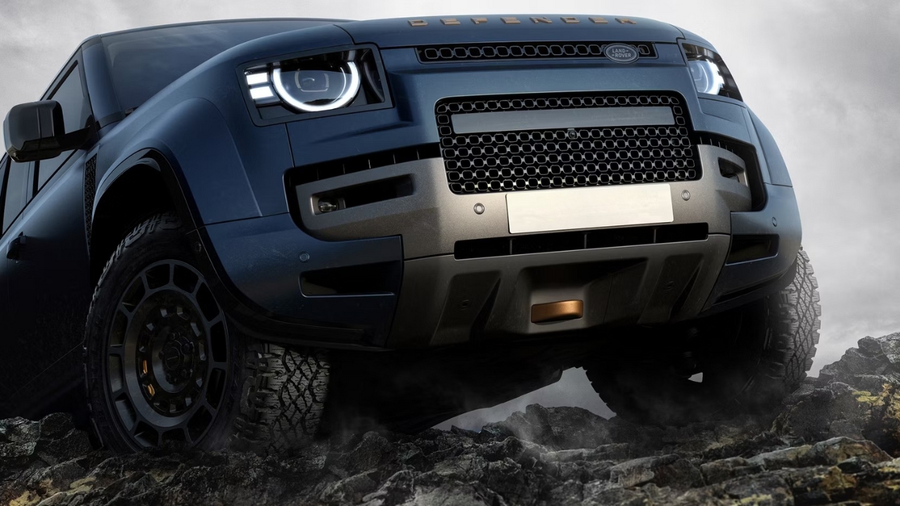 Low-angle view of the Land Rover Defender OCTA front grille and bumper driving over rocky ground.