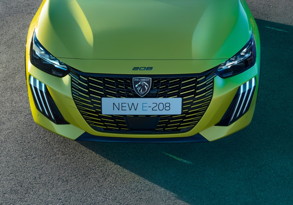 Peugeot E-208 electric hatchback front grille and badge detail with distinctive LED daytime running lights.