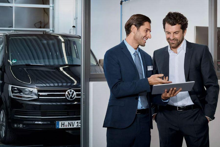 Volkswagen salesmen in front of Volkswagen vehicle