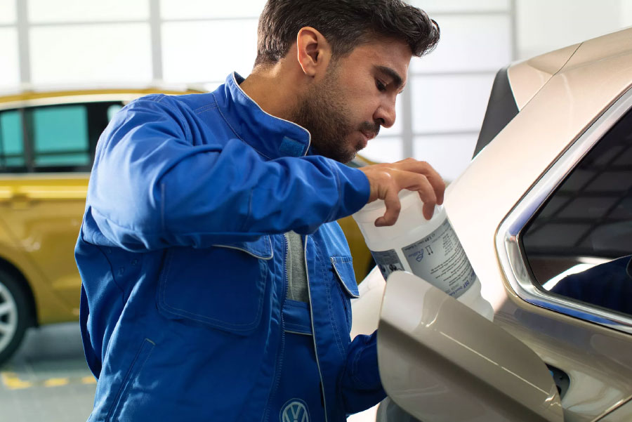 Volkswagen Mechanic pouring ADBLUE into VW
