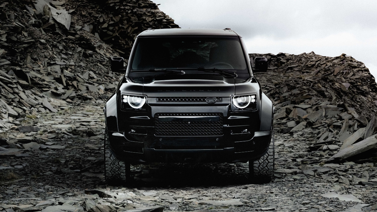 Front view of the Defender OCTA Black driving through a rugged rocky landscape.