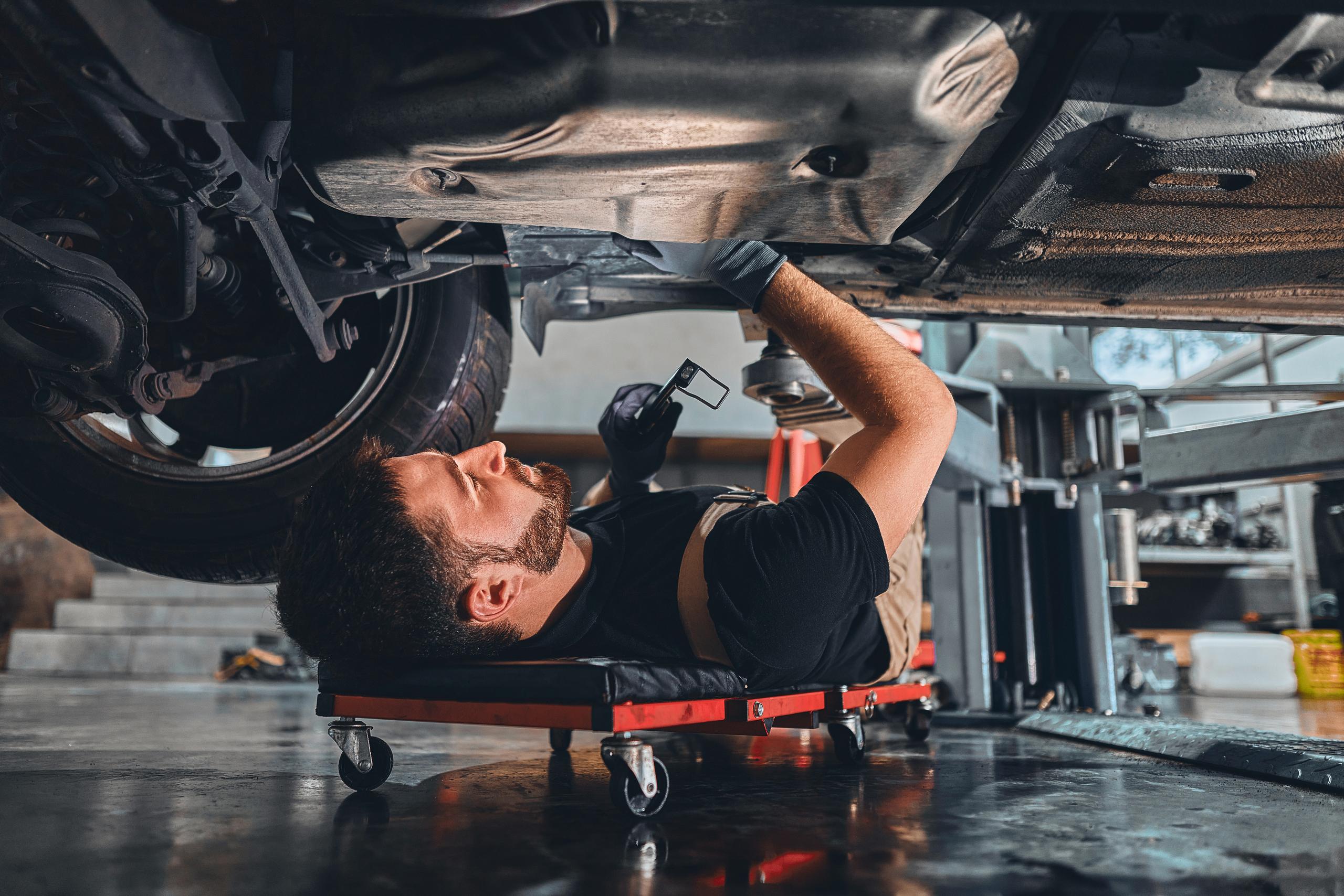 Mechanic lying down looking under the car