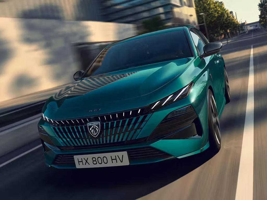 Front three-quarter view of the new Peugeot 308 in striking green metallic, featuring signature LED fang daytime running lights, bold vertical grille and sculpted bonnet lines.