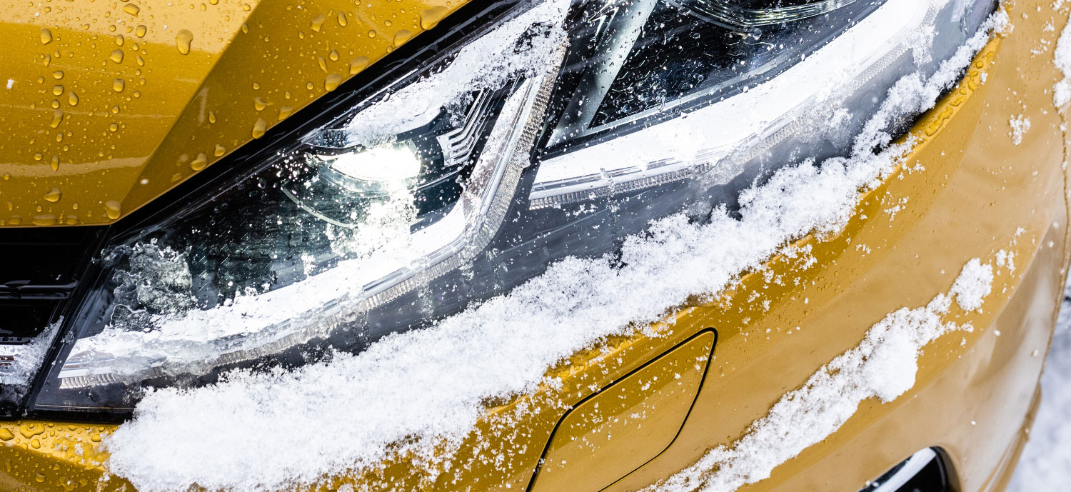 Yellow Volkswagen headlight with snow on