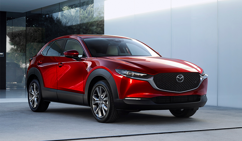 A shiny red mazda cx-30 parked in front of a concrete back drop.