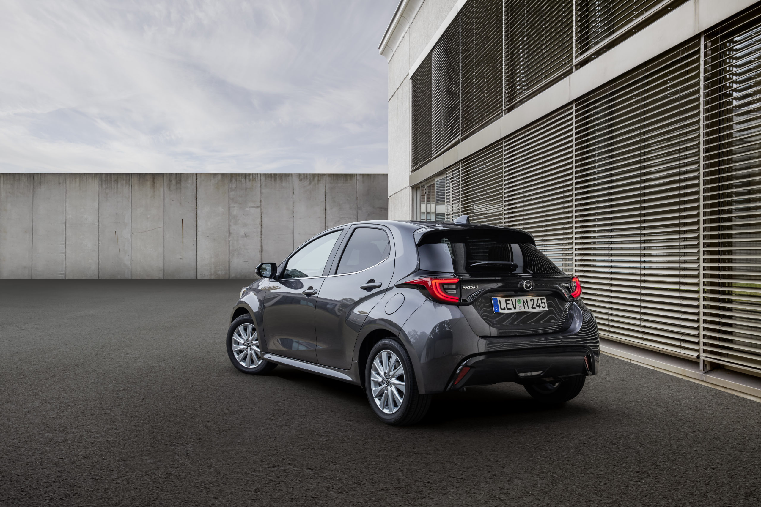 Mazda 2 hybrid in city environment in front of building.