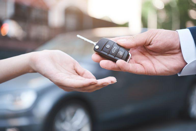 Sales person handing car key to customer