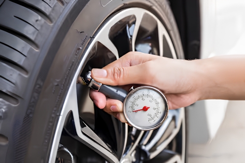 Checking tyre pressure with a pressure gauge to ensure safe driving.