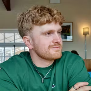Person seated indoors wearing a green top and looking to one side.