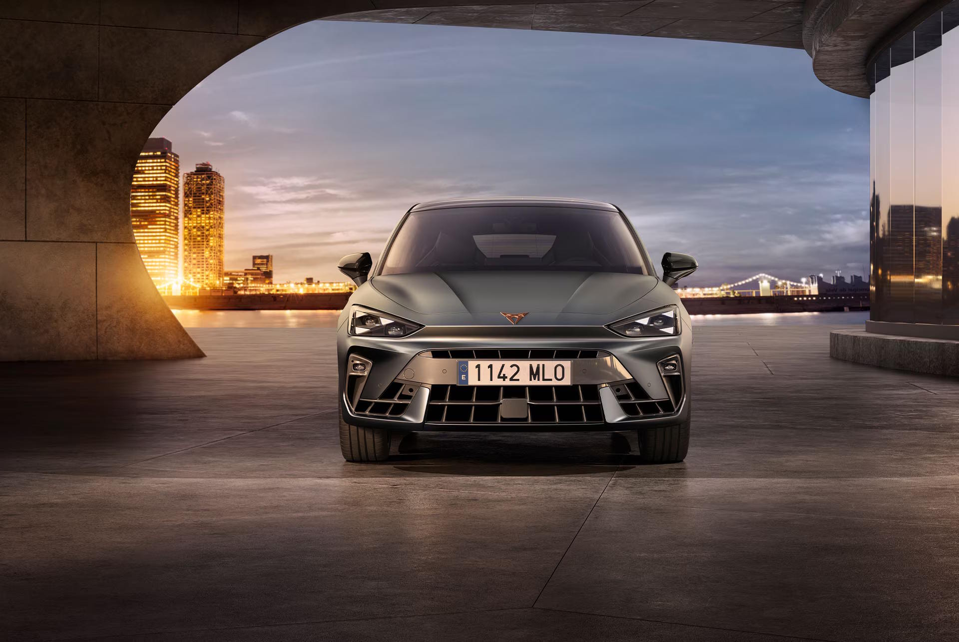 CUPRA Leon facing forward in a modern urban setting at sunset.