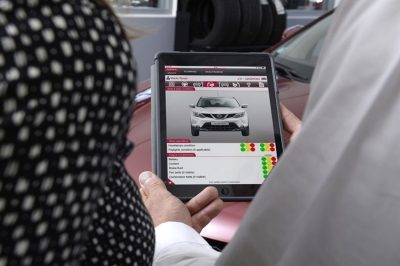 Two buyers looking at a Nissan Welcome Check on a tablet