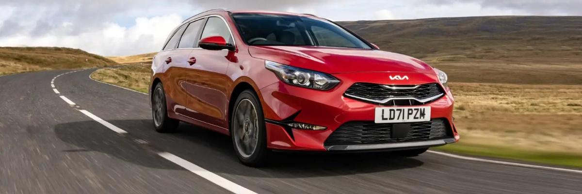 Red Kia Ceed Sportswagon driving through a hilly landscape