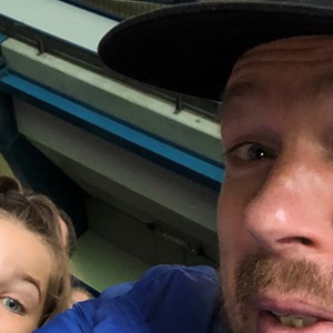 Partial selfie of two people captured from a close angle indoors.