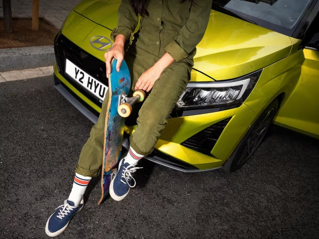 Person holding a skateboard learning on Hyundai i20
