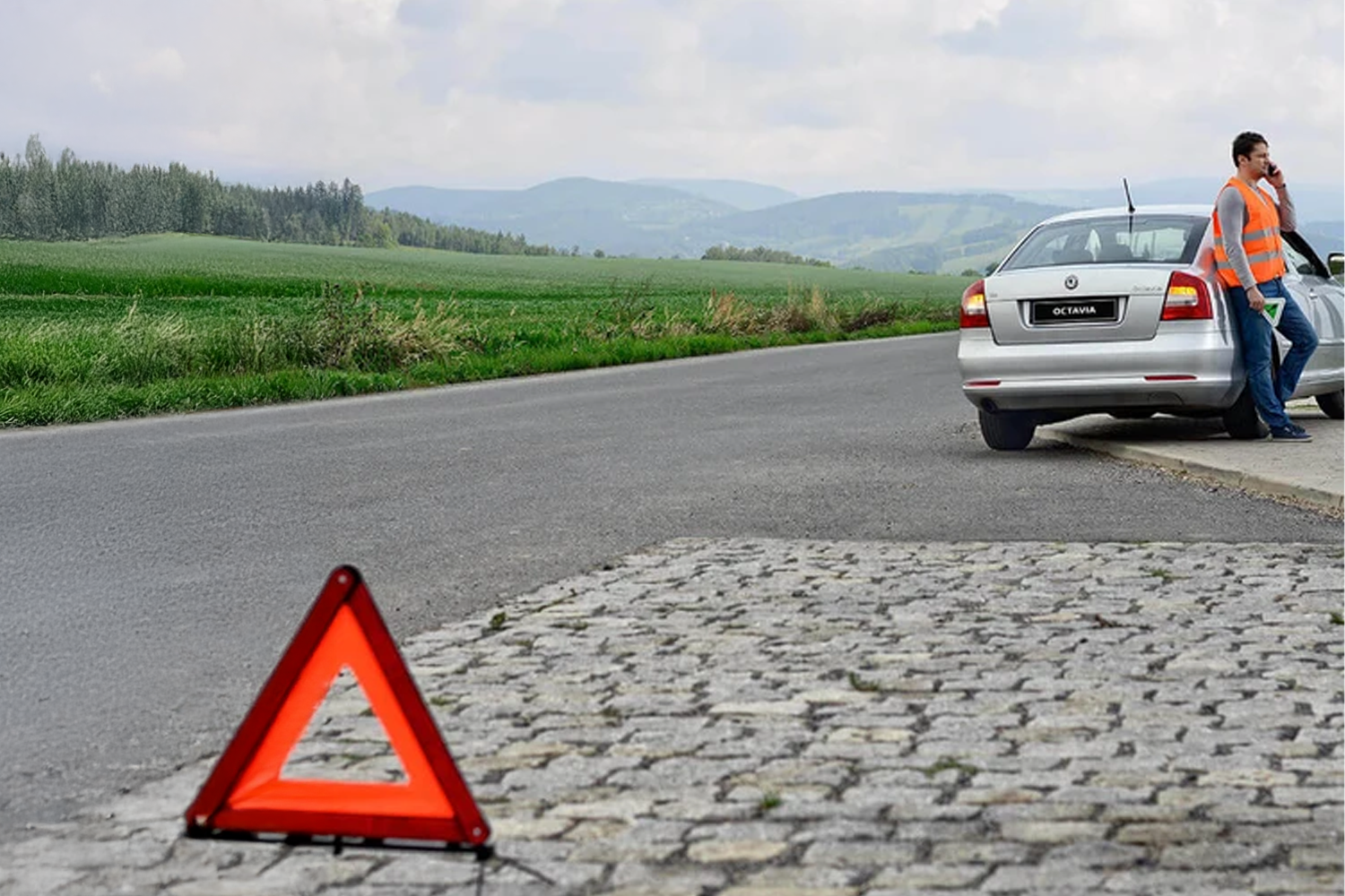 Person pulled over on side of the road with hazard sign