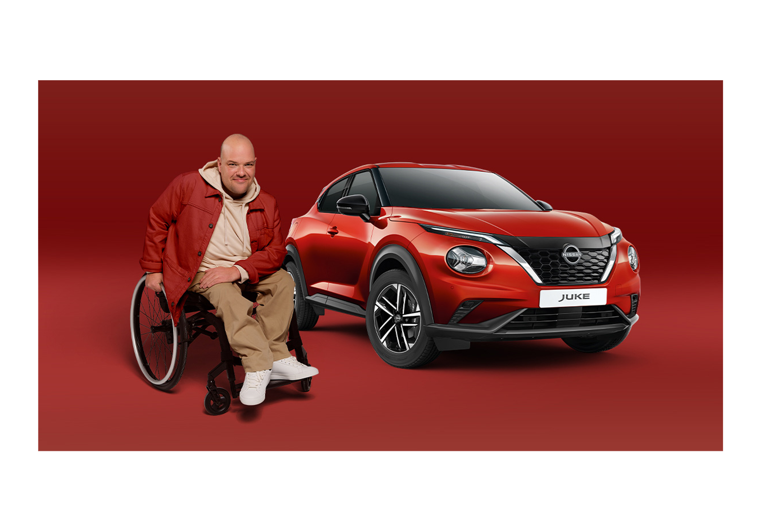 man in wheelchair next to a red nissan JUKE