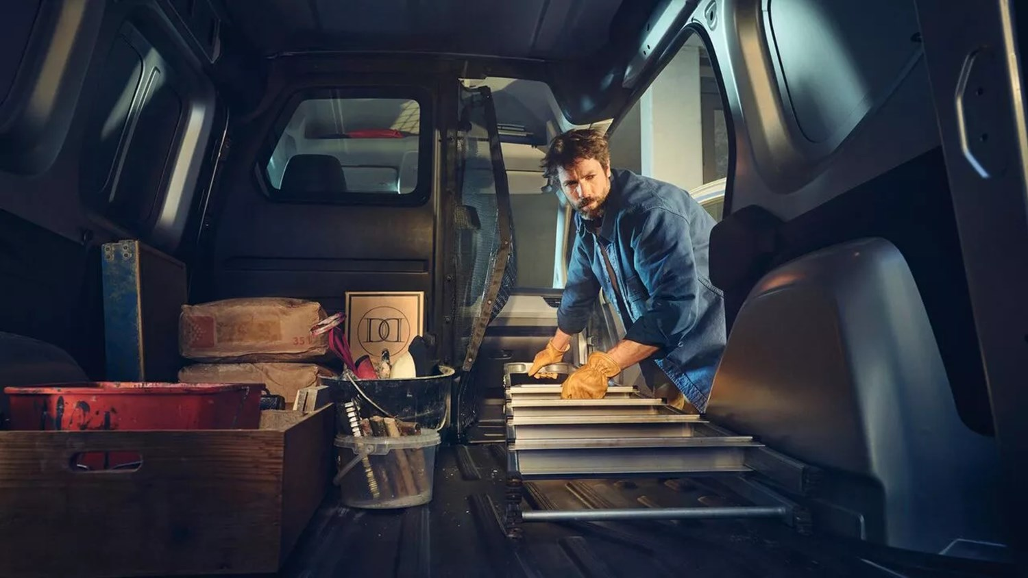 Renault van interior with a worker loading tools and equipment in the cargo area.
