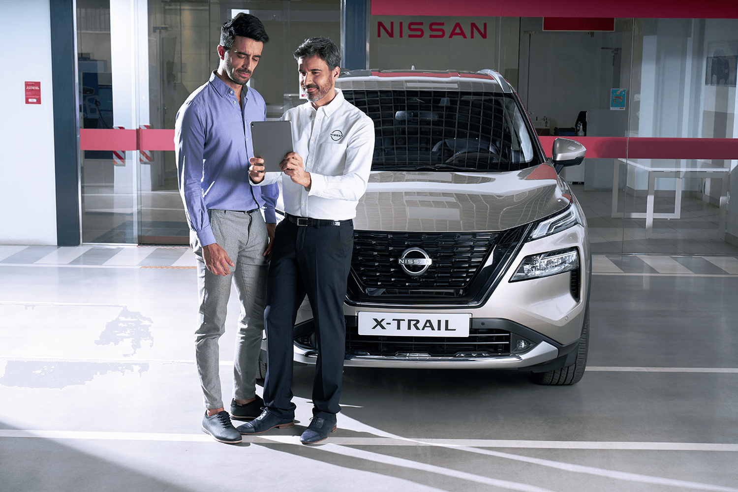 Nissan employee showing customer something on his ipad infront of Nissan X-Trail