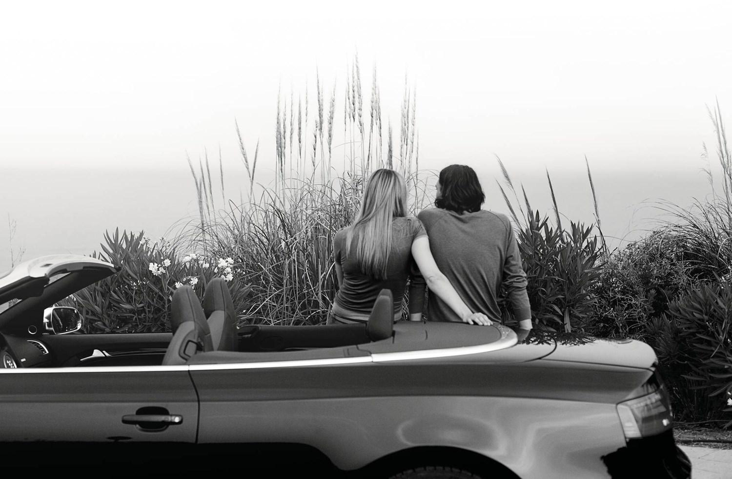 Couple sat by convertible Audi