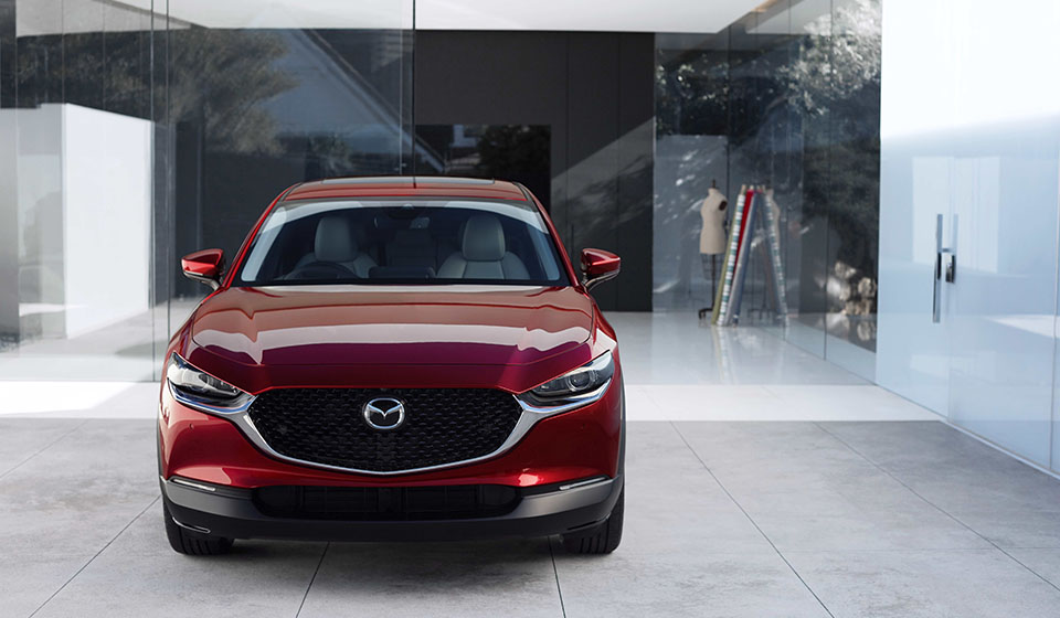 A red mazda cx-30 parked outside an empty gallery.