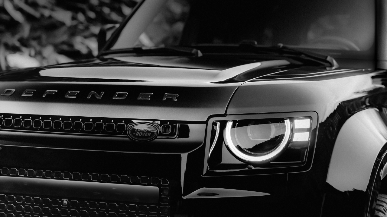Close-up detail of the Defender OCTA Black front headlight, grille, and DEFENDER badge.