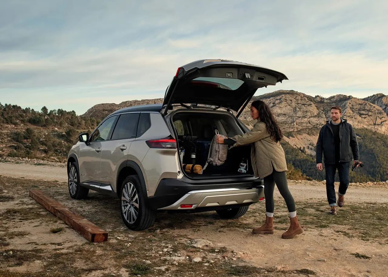 Bronze Nissan X-Trail parked on dirt road with boot open
