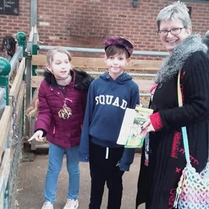 Children and an adult smiling together while holding event materials at a public attraction.