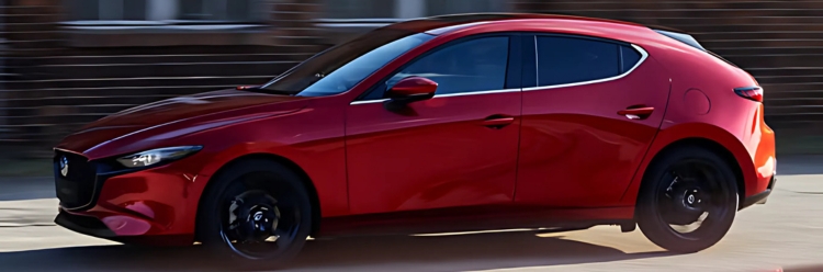 Mazda3 Hatchback in red driving in an urban road