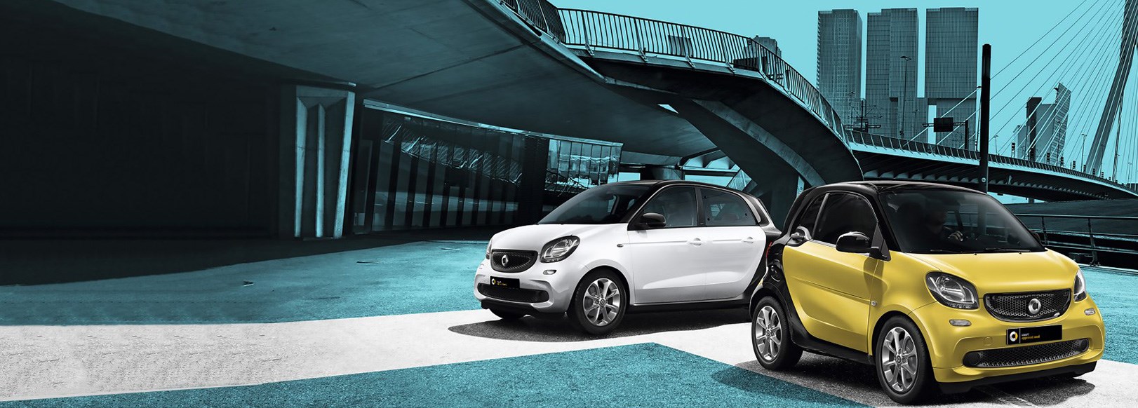 A white and a yellow Smart car parked under a bridge