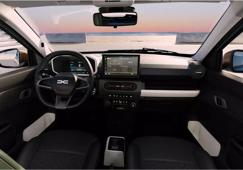 Dacia Spring interior dashboard with central touchscreen and steering wheel, overlooking a coastal landscape through the windscreen.