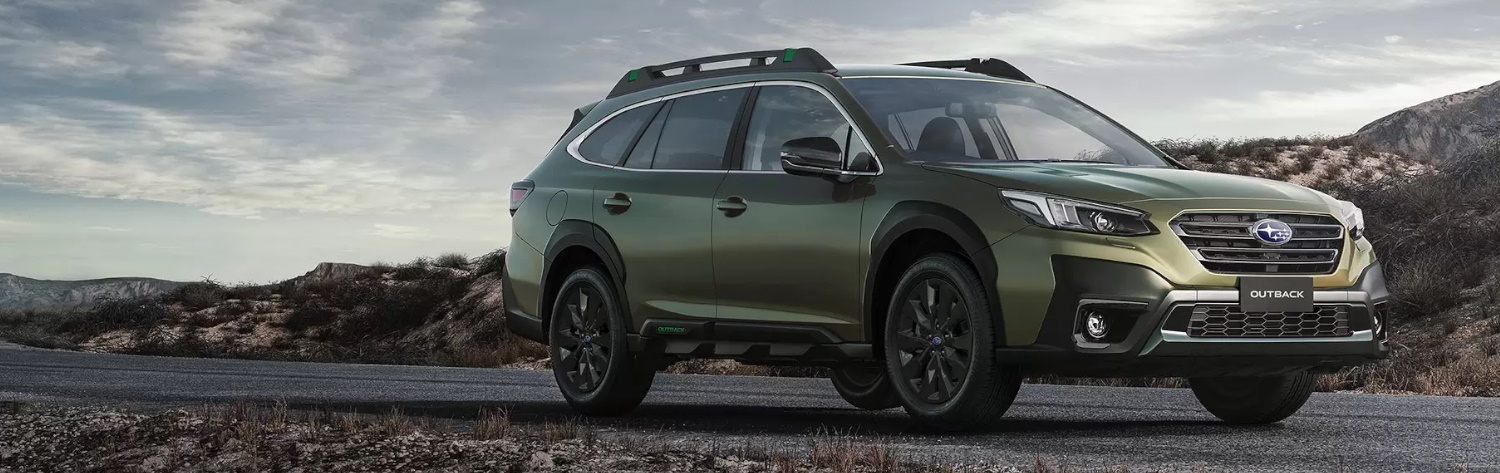Green Subaru Outback by the mountains