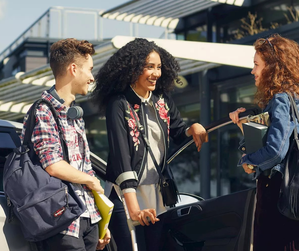 Group of people talking next to open car door