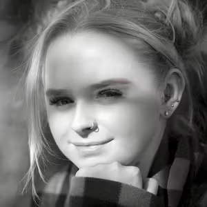 Black and white portrait of a person resting their chin on their hand outdoors.