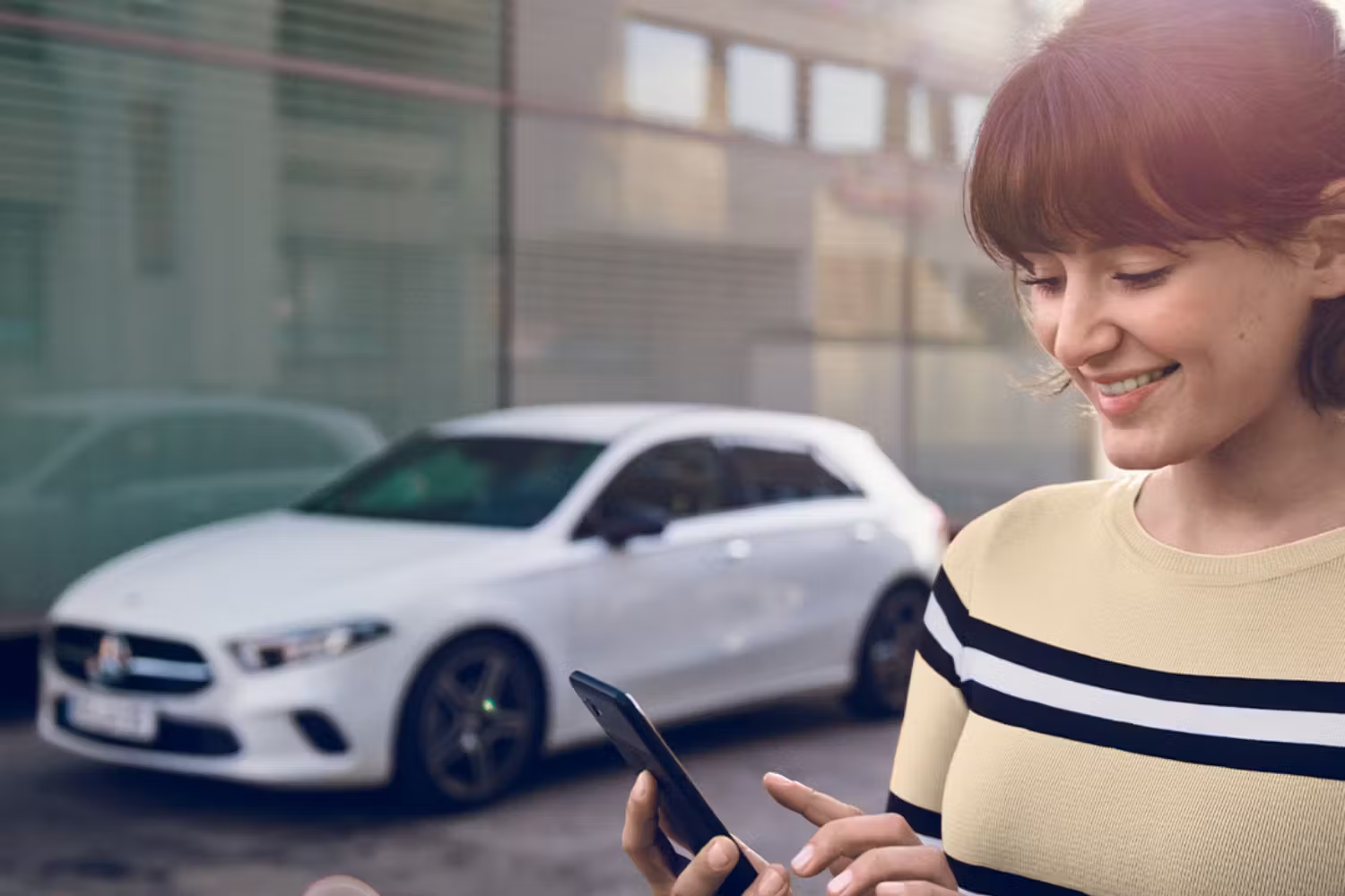 Person on smartphone in front of White Mercedes-Benz