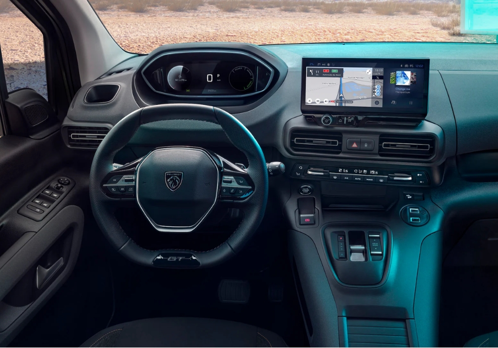 Interior of Peugeot E-Rifter showing steering wheel, digital instrument cluster, center touchscreen, and gear controls.