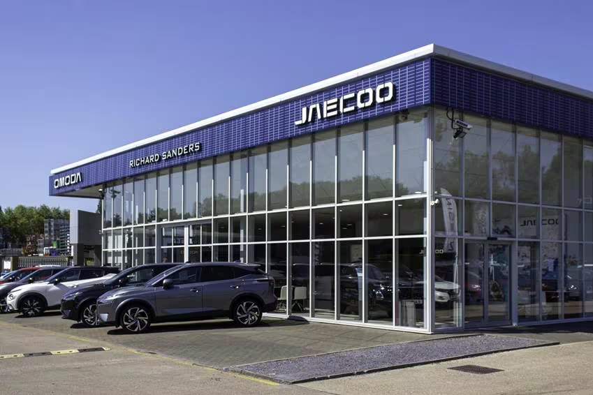 Exterior view of Jaecoo dealership with glass façade and vehicles displayed outside the showroom.