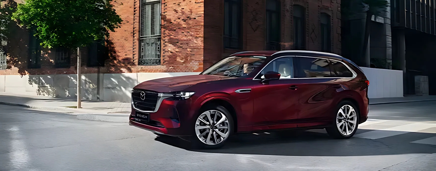 Red Mazda CX-80 driving through an urban environment.