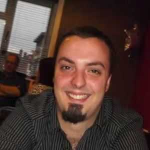 Casual indoor portrait of a person seated at a table in a restaurant setting.