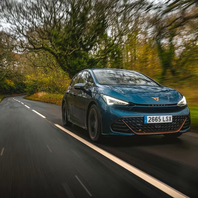 Blue CUPRA Born driving along a winding forest road.