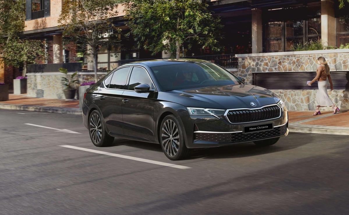 Black Skoda Octavia saloon driving through a stylish urban street.