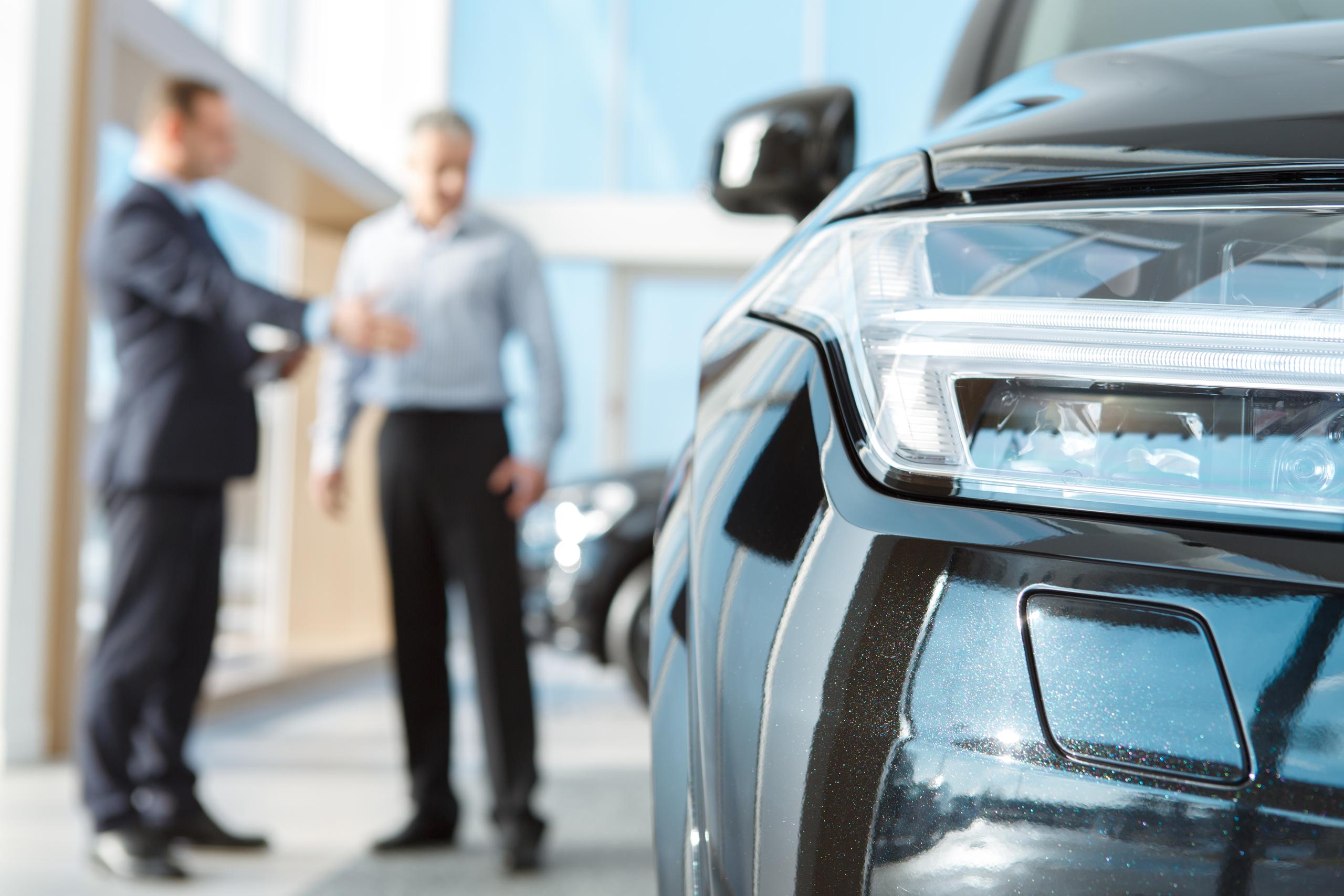 stock image of sales person next to car